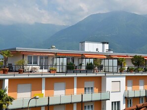 Experience the hotel's modern design with stunning views of the surrounding mountains from the balconies, equipped with outdoor furniture and potted plants.