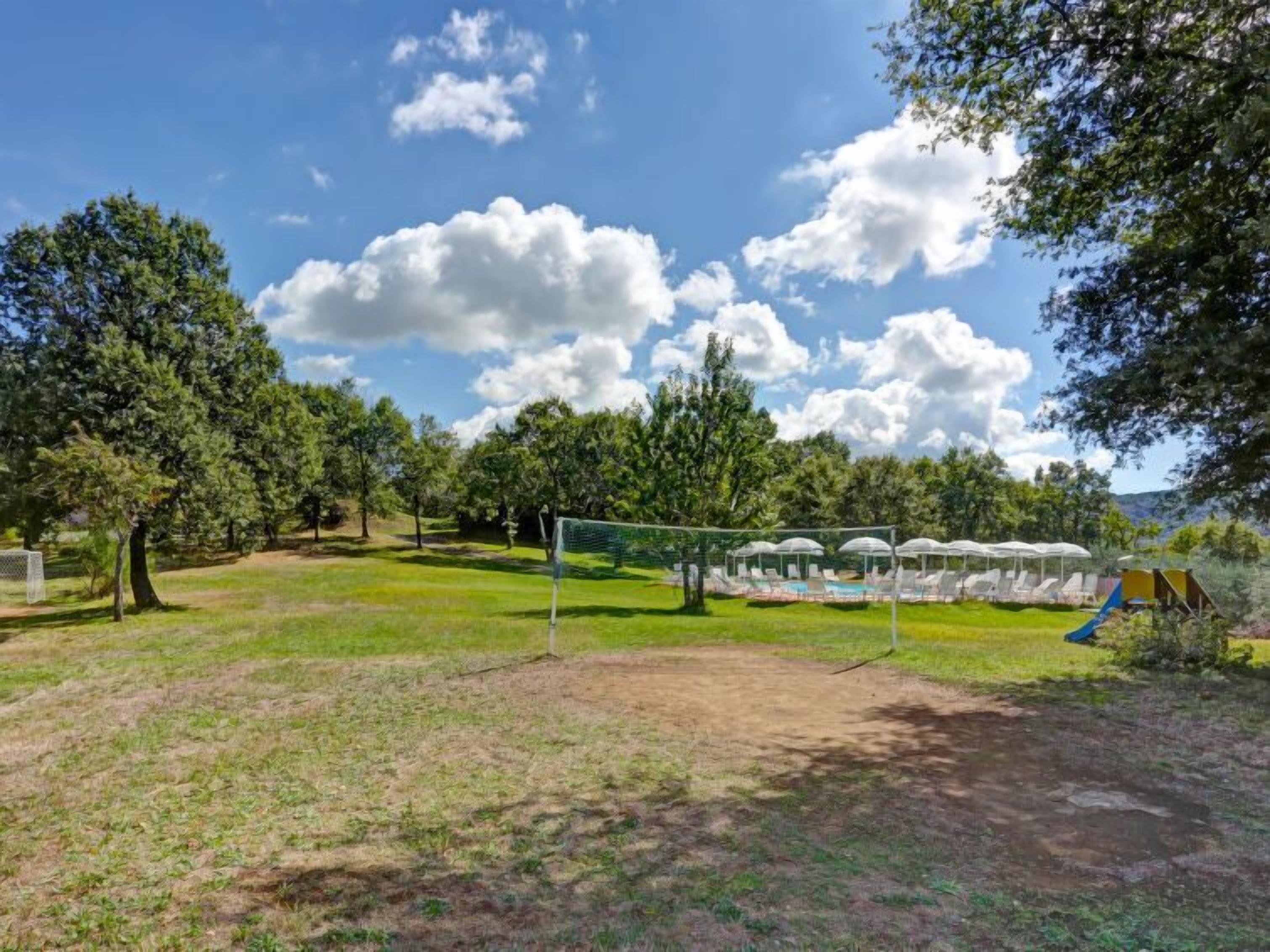 A grassy outdoor area with a soccer goal, lounge chairs, and a playground.
