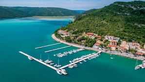 Un pueblo costero con un puerto deportivo, casas y colinas al fondo.