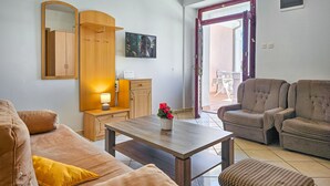 Una sala de estar con un sofá, una mesa de centro con un florero, un televisor y un mueble de madera.