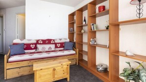 Uma sala de estar acolhedora com um sofá de madeira, uma pequena mesa de madeira e prateleiras embutidas de madeira.