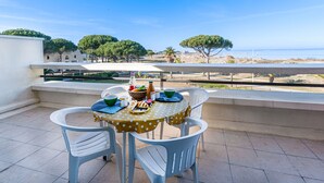 Ein Balkon mit Tisch für zwei Personen mit Blick auf Strand und Bäume.