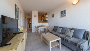 Ein modernes Wohnzimmer mit einer Couch, einem Holztisch und einem Fernseher auf einer Holzkommode.