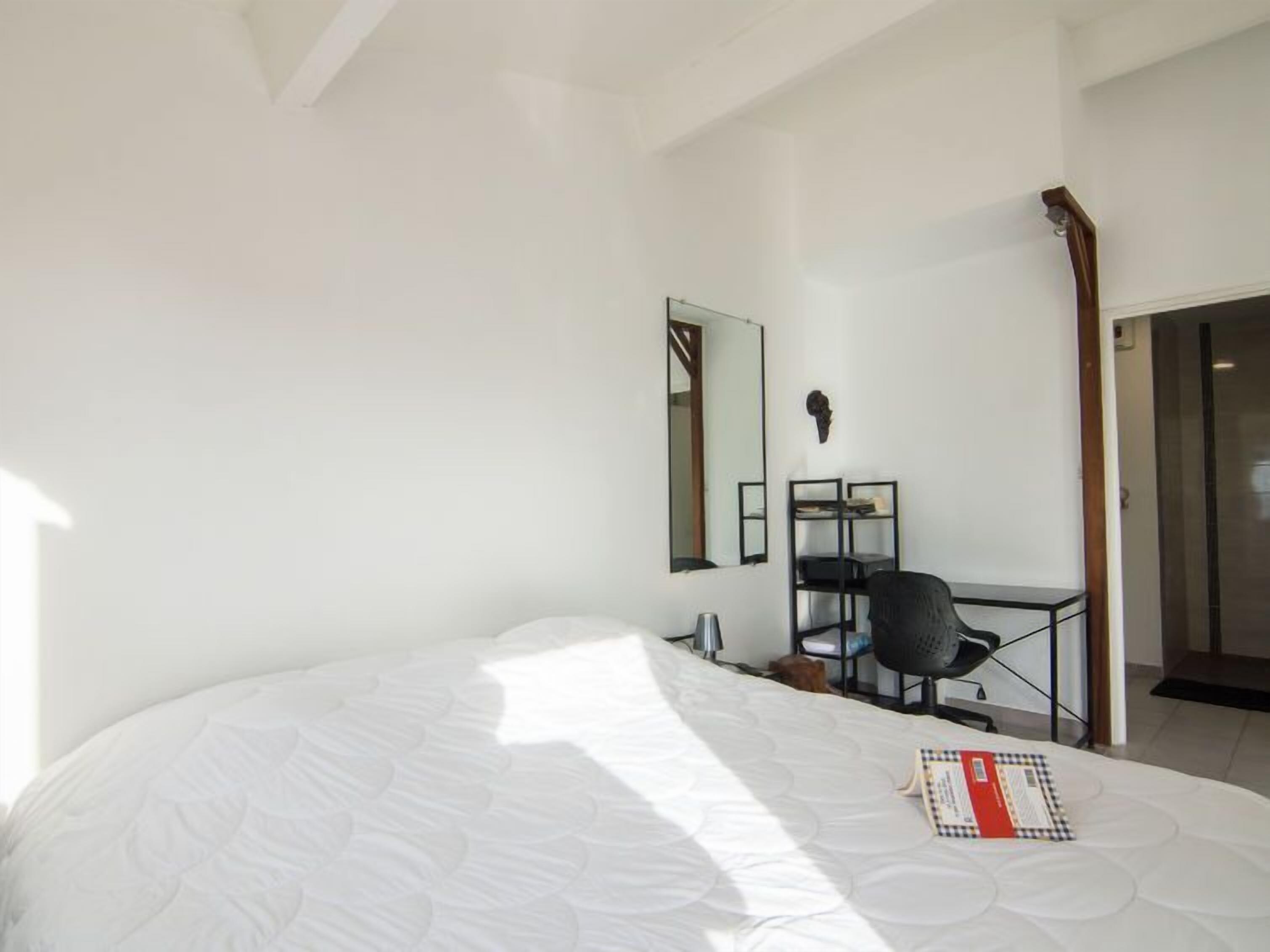 Une chambre à coucher avec un grand lit, un bureau, une chaise, un miroir et une armoire.