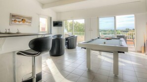 Ein modernes Wohnzimmer mit Billardtisch, Bar und großen Fenstern mit Blick ins Freie.