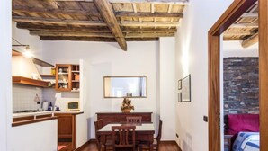 A compact kitchen with wooden cabinets and a dining area with a wooden table and chairs. - Domus Fori by Interhome (Rome: Historical City Center)