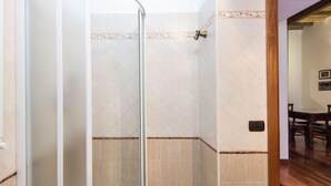 A bathroom with a glass shower enclosure, tiled walls, and a wooden floor. - Domus Fori by Interhome (Rome: Historical City Center)