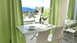 Ein Essbereich mit einem Tisch für zwei Personen, einer Weinflasche und einem Blumentopf.