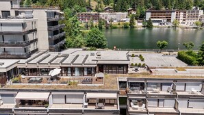 Ein modernes Hotel mit mehreren Etagen, Außenbereichen zum Sitzen und Blick auf einen See.