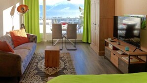 Ein modernes Zimmer mit einer Couch, einem Fernseher, einem Schrank und Blick auf Berge durch das Fenster.