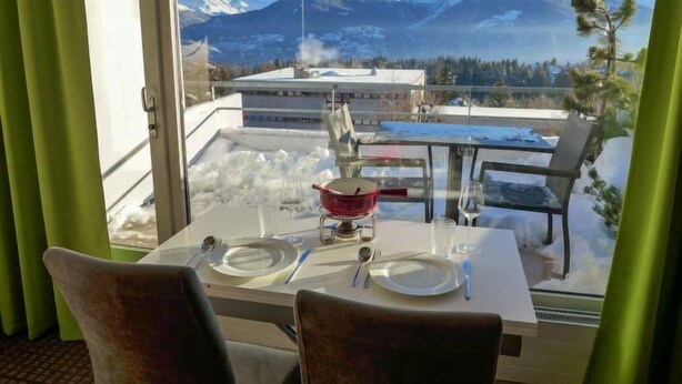 Ein Essbereich mit Tisch für zwei Personen, mit Blick auf eine verschneite Landschaft und Berge.