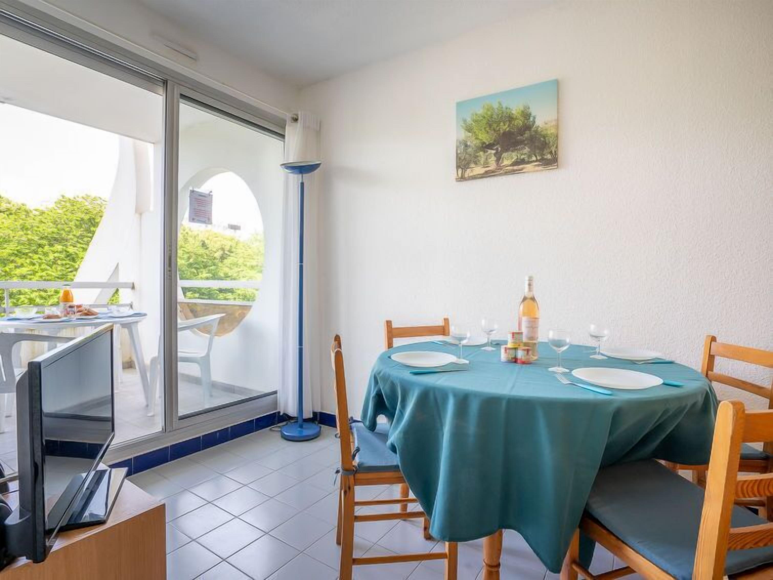 Un comedor con una mesa dispuesta para dos, una botella de vino y un cuadro en la pared.