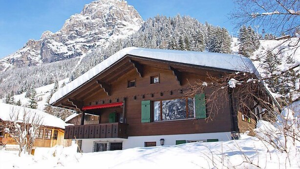 A wooden chalet with a sloped roof, a balcony, and a view of snow-covered mountains. - Chalet Marietta by Interhome (Kandersteg)