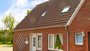 Una casa in mattoni rossi con tetto a tegole, un piccolo portico e una finestra con tenda.