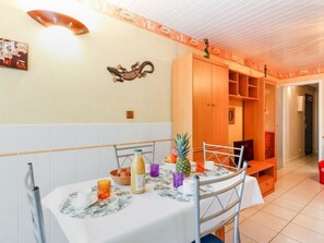 Een eethoek met een tafel gedekt voor twee personen, een houten kast en een decoratief object aan de muur.