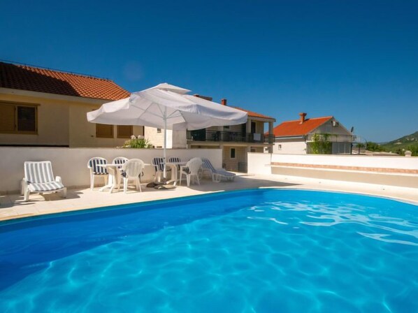 Relax by the serene pool surrounded by comfortable lounge chairs and a shaded area.