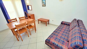 Una sala de estar con un sofá, una mesa de comedor con sillas y una mesita.