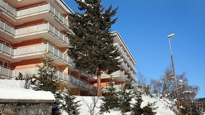 Un hôtel à plusieurs étages doté de balcons, un paysage enneigé et un ciel bleu dégagé.