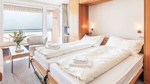 Une chambre d’hôtel avec deux lits, un bureau, une chaise, une télévision et une vue sur la mer.