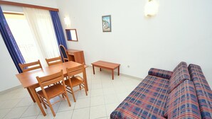 Een woonkamer met een bank, een eettafel met stoelen en een bijzettafeltje.