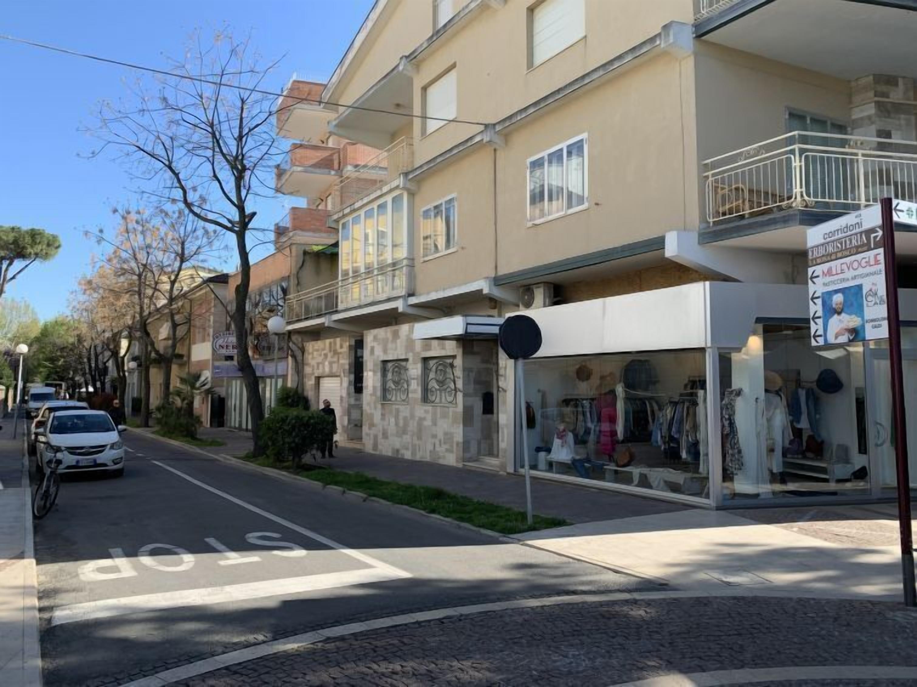 A street view with a row of buildings, including a shop with a signboard.