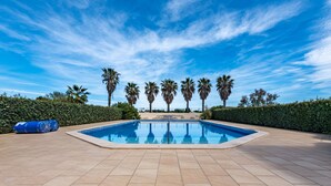A swimming pool with a tiled deck, surrounded by palm trees and a clear blue sky. - Les Embruns by Interhome (Saint Cyprien)