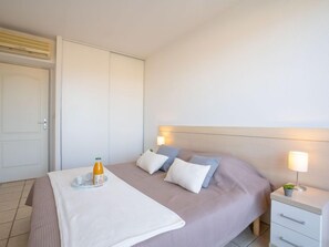 Um quarto bem arrumado com cama, mesas de cabeceira e criadeira.
