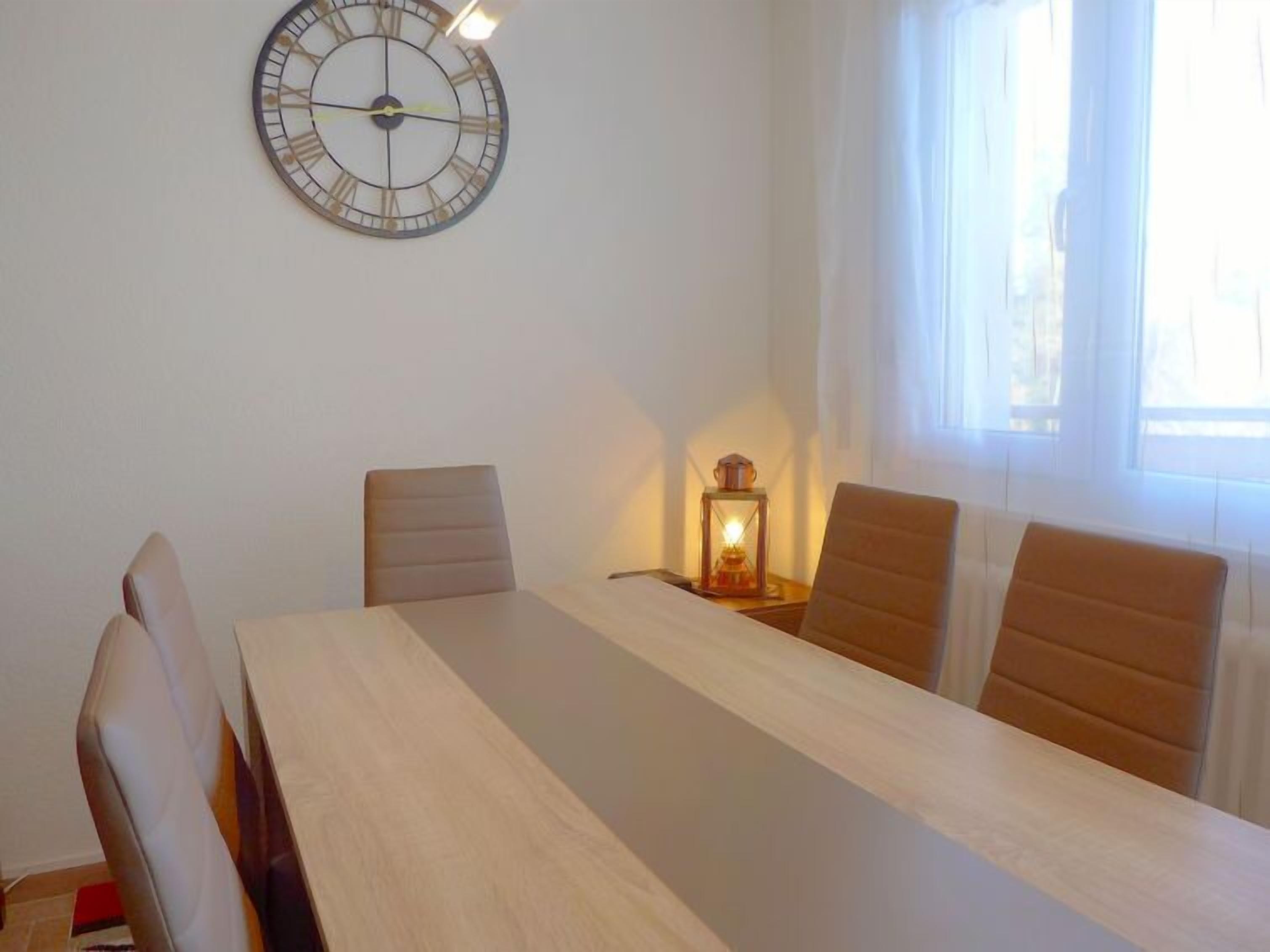Une salle de conférence avec une longue table, quatre chaises, une horloge murale et une lanterne allumée.