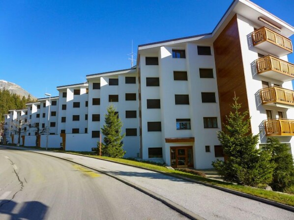 Un hotel de varios pisos con un diseño moderno, con balcones en los pisos superiores y una vista despejada del paisaje circundante.