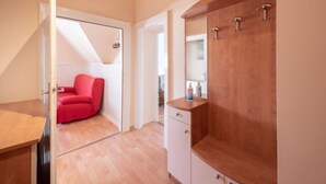 Une chambre à coucher moderne avec un fauteuil rouge, une armoire en bois et une table de chevet blanche.