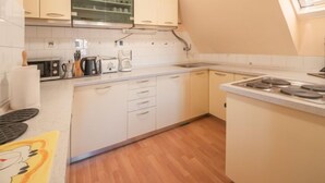 Une cuisine compacte avec des meubles blancs, un four à micro-ondes, une machine à café et une cuisinière.