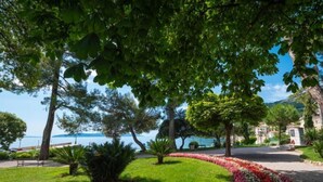 Un jardin aménagé avec un parterre de fleurs aux lignes courbes, un banc et une vue sur la mer.
