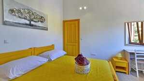 Une chambre à coucher avec un lit, une porte en bois, un bureau avec une chaise et une fenêtre.