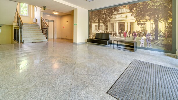 Tilava aula, jossa on portaikko, suuri seinämaalaus ja oleskelualue.