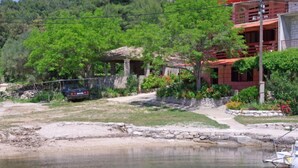 A house with a stone foundation, surrounded by lush greenery and a small pond.
