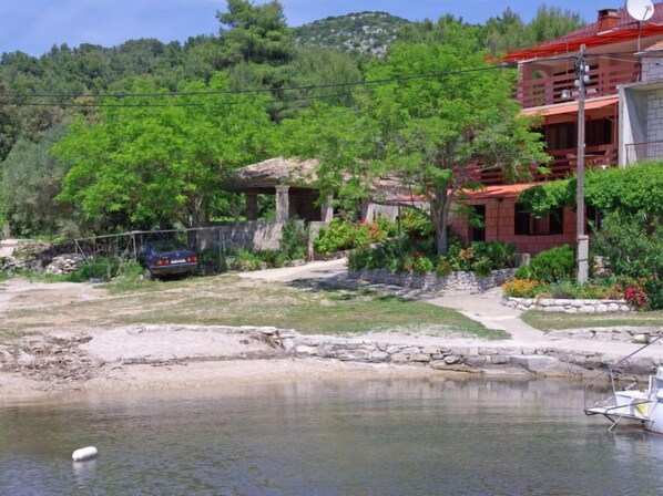 A house with a stone foundation, surrounded by lush greenery and a small pond.
