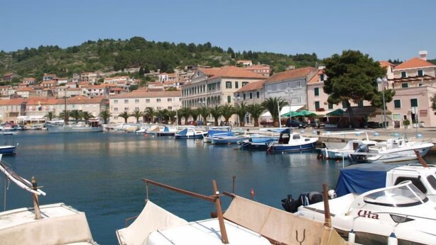 A marina with boats docked, surrounded by buildings with red-tiled roofs.