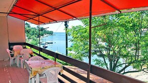 A balcony with outdoor seating, overlooking a body of water and greenery.