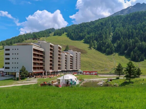 A multi-story hotel with a flat roof and a large outdoor area with a tent.