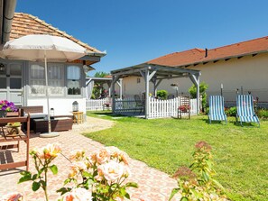 Eine Terrasse mit Gartenmöbeln, einer Pergola und einem weißen Zierzaun.