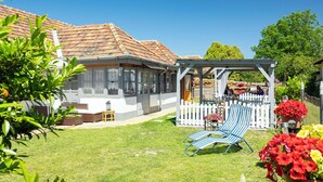Een huis met een overdekte veranda, een gazon en een tuin vol bloemen.