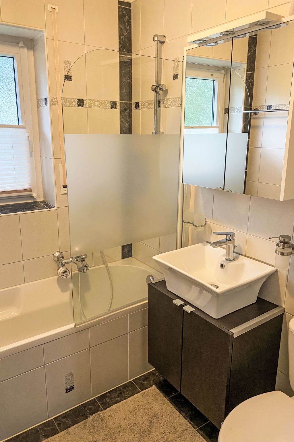 A bathroom with a bathtub, a sink, a toilet, and a window.