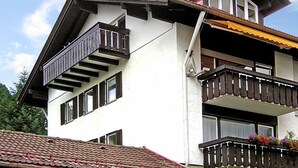 Ein zweistöckiges Gebäude mit einem Balkon im oberen Stockwerk und einem kleineren Balkon im unteren Stockwerk.