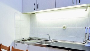 A compact kitchen with white cabinets, a stove, and a sink. - Meridiana by Interhome (Orebic)