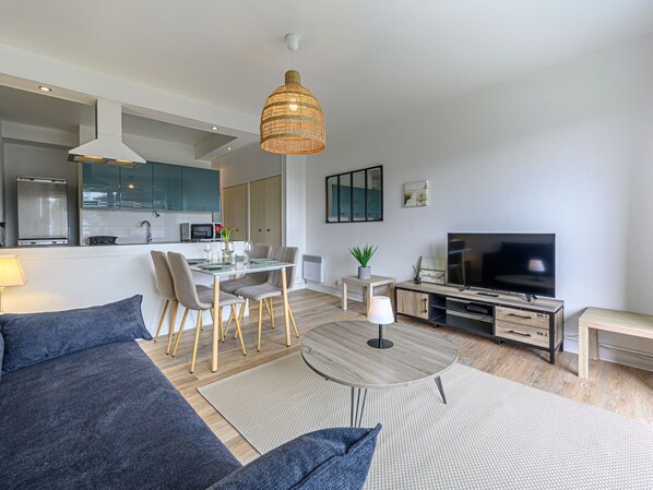 A modern living room with a sofa, dining table, and TV.