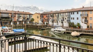 A canal with boats, colorful buildings, and a mountain in the background.