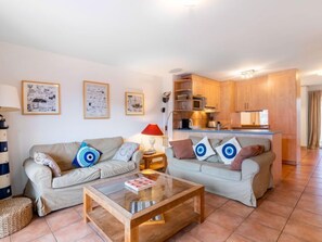 A compact living space with two sofas, a coffee table, and a kitchenette.