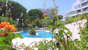 Un espace piscine avec une eau d’un bleu limpide, entouré d’une végétation luxuriante et de plantes en fleurs.
