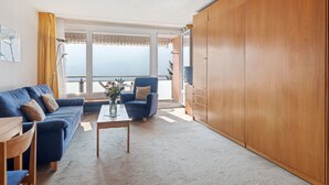A modern living room with a blue sofa, a coffee table, and a wooden wardrobe. - Promenade Apt 306 by Interhome (Arosa)