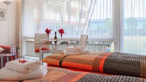 A hotel room with a bed, a small table with a chair, a radiator, and large windows with sheer curtains. - Residenza Lido Appartment 009 by Interhome (Locarno)